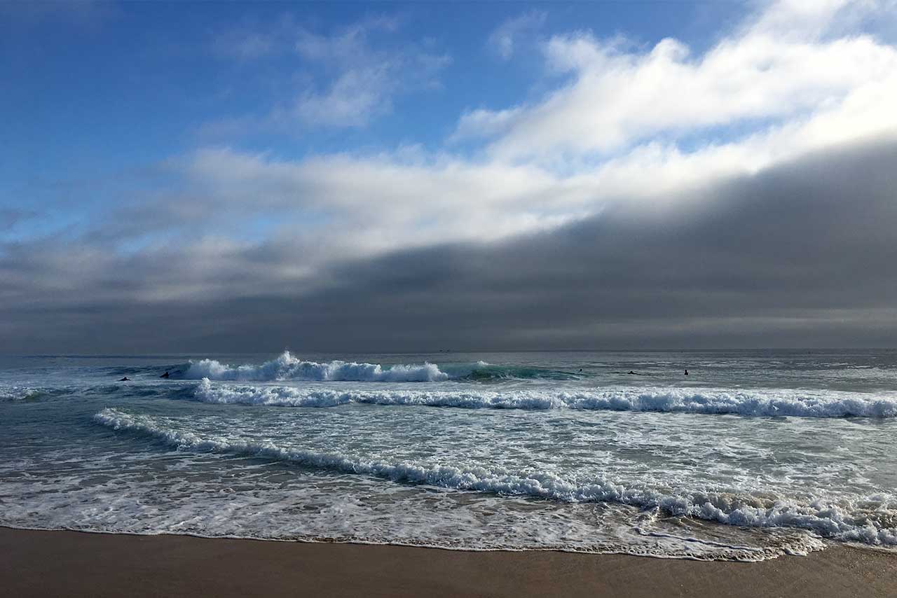 wellen treffen auf sandstrand unter wolkenhimmel